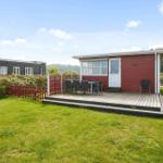 Rotes Ferienhaus mit Terrasse und Garten. Tisch und Stühle auf der Veranda.