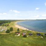 Strandnahe Ferienhäuser mit Campingplatz und grüner Landschaft.