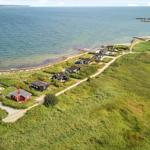Rotes Strandhaus mit Garten, umgeben von Grünflächen und Meer.