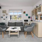 Wohnzimmer mit Sofa, zwei Sesseln und Küchenzeile.