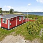Rotes Strandhaus mit Garten und Blick aufs Wasser.