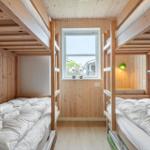 Zimmer mit zwei Etagenbetten, Holzwand und Fenster.