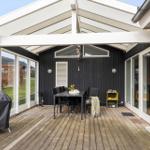 Terrasse mit Tisch, Stühlen und Grill unter weißem Dach