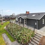 Schwarzes Haus mit Terrasse und Garten. Flagge weht im Wind.