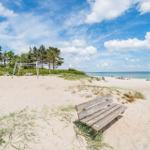 Holzbank auf Sandstrand mit Blick auf Meer und Himmel