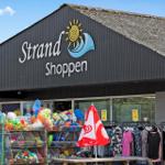 Strand Shoppen Laden mit Strandartikeln und Kleidung im Vordergrund.