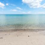Strand mit klarem Wasser und blauem Himmel.