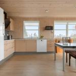 Küche mit Essbereich, Holzwand und Fenstern. Esstisch mit Stühlen und Deckenleuchte.