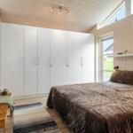 Schlafzimmer mit Bett, Kleiderschrank und Fenster.