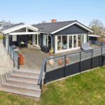 Moderne Villa mit großem Holzterrasse, Garten und Terrassentür zur Küche.