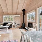 Wohnzimmer mit Holzwand, Kamin und Essbereich mit Tischdecke.