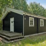 Holzhütte mit weißen Fensterrahmen und Tür. Nummer 9. Umgeben von Bäumen und Gras.