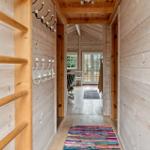 Flur mit Holzwand und buntem Teppich führt in Wohnbereich.