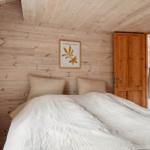 Schlafzimmer mit Holzwand, Bett und Bild an der Wand.