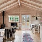 Wohnraum mit Holzdecke, Kamin und Essbereich mit Tisch und Stühlen.