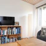 Wohnzimmer mit Fernseher, Bücherregal und Sessel.