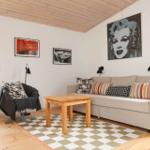 Wohnzimmer mit Sofa, Tisch, Teppich und Wandbildern.