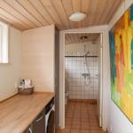 Badezimmer mit Dusche und Waschmaschine. Wandbild und Holzdecke.