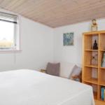 Schlafzimmer mit Bett, Fenster, Bücherregal und Wandbild.