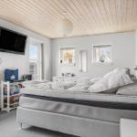 Schlafzimmer mit Bett, Fernseher und Fenstern.
