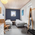 Zwei Betten, Kleiderständer und Fenster in einem Schlafzimmer mit Holzdecke.