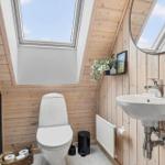 Badezimmer mit Toilette, Waschbecken und Dachfenster. Holzwände und graue Wand.