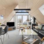 Wohn- und Essbereich mit Holzdecke, Sofa, TV und Fenstern.
