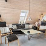 Wohnraum mit Holzwand, Sofa, Stühlen und Kamin.