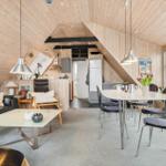 Wohnbereich mit Essbereich, Holzdecke und Fenster. Sofa, Tisch und Stühle sichtbar.