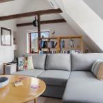 Wohnzimmer mit grauem Sofa, Holztisch und Bücherregal unter Dachschrägen.