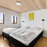 Schlafzimmer mit Doppelbett, Holzdecke und zwei Fenstern.