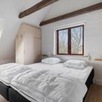 Schlafzimmer mit Doppelbett, Holzbalken und Fenstern