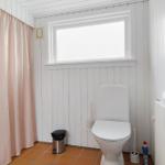 Badezimmer mit Toilette, Fenster und rosa Duschvorhang.