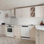 Küche mit hellen Schränken, Spüle und Backofen. Dachschrägen Decke und Fenster.