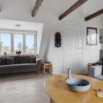 Wohnraum mit Holzbalken, Sofa, Tisch und Fenster