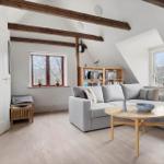 Wohnzimmer mit grauem Sofa, Holztisch und Bücherregal unter Dachschrägen.