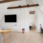 Wohnzimmer mit TV, Couch und Tisch unter Holzbalken