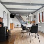 Haus mit Esstisch, Kamin und Treppe zur oberen Etage.