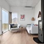 Wohnraum mit Kamin, Sofa und Fernseher. Große Fenster mit Blick auf die Landschaft.