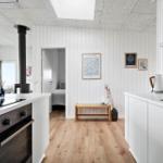 Küche mit Holzboden, weißen Schränken und Blick in Schlafzimmer