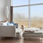 Wohnzimmer mit Sofa, Sitzbank und großem Fenster zur Landschaft.