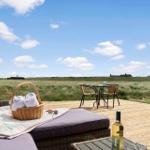 Terrasse mit Liege, Tisch und Stühlen, Blick auf Grasland und Himmel.