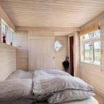 Schlafzimmer mit Holzwänden, Bett und Fenstern mit Blick.