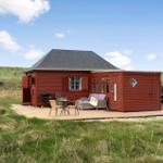 Rotes Holzhaus mit Terrasse, Grill und dänischer Flagge im Grasland.