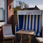 Terrasse mit Strandkorb, Tisch und zwei Stühlen vor Hauswand.