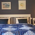 Schlafzimmer mit Bett, zwei Nachttischen und Wandbildern.