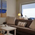 Wohnzimmer mit Sofa, Tisch und Wandbild. Fenster mit Jalousie.