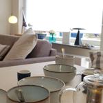 Esstisch mit Tassen und Tassen, Sofa und Fensterblick.