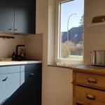 Küche mit dunklen Schränken, Fenster und Holzschrank. Auf dem Fensterbrett liegen Süßigkeiten.