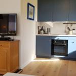 Küche mit blauen Schränken und Holzmöbeln. Fernseher auf einem Schrank.